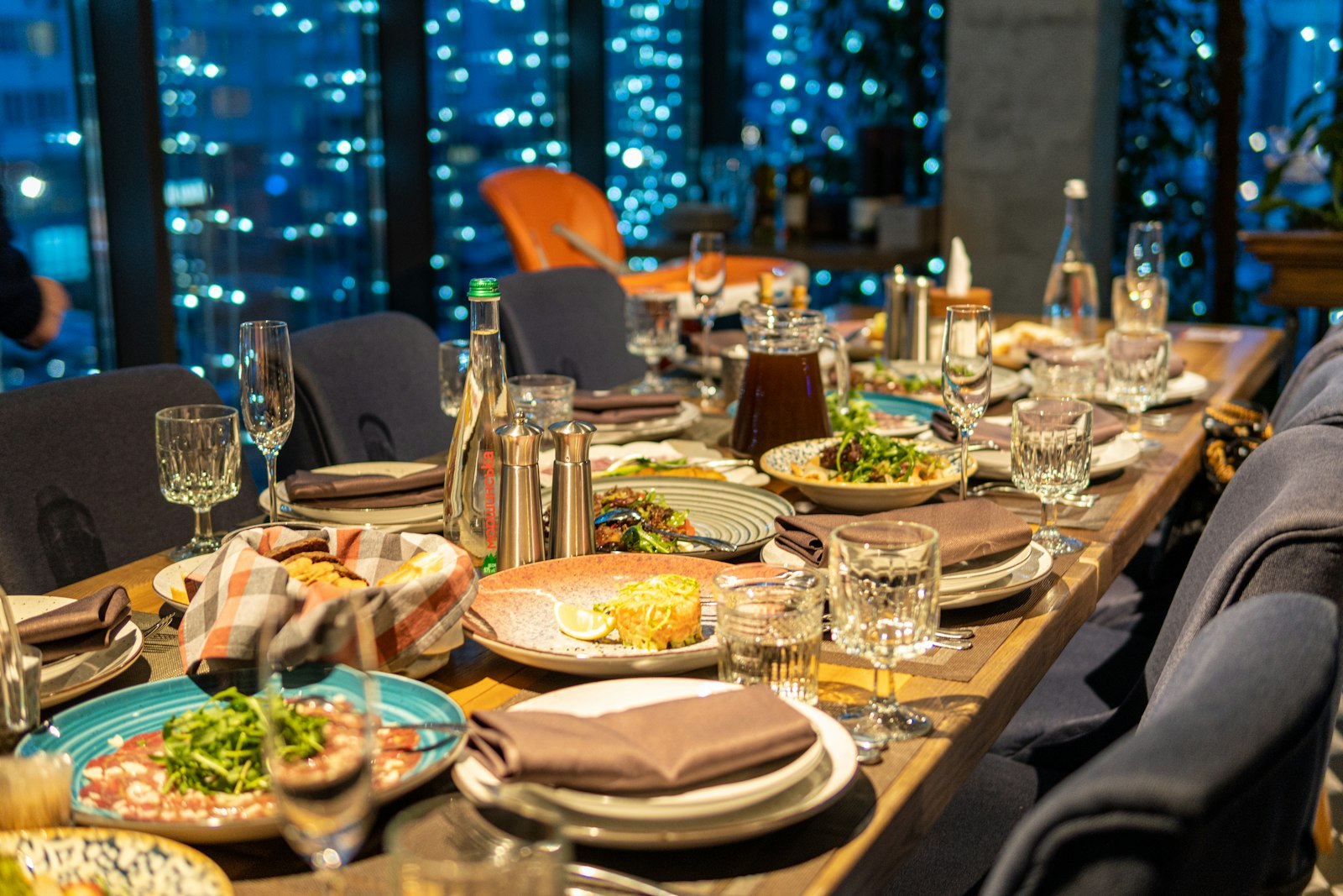 A restaurant table set for dinner with a city view
